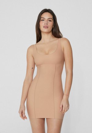 Vestido ajustado nude con escote en forma de barco, tirantes finos y detalles de costura, elaborado con una tela suave y elástica para un ajuste ceñido al cuerpo.