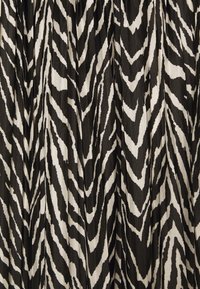 Tela en blanco y negro con un diseño audaz de cebra, con rayas angulares que crean un aspecto texturizado en toda su superficie.