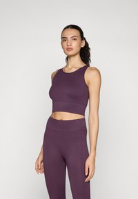 Lilla ribbet crop top og højtaljede leggings i et sømløst design, der har en glat tekstur og en tætsiddende silhuet.