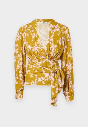 Blusa avvolgente floreale in giallo senape con motivi di fiori rosa, maniche lunghe e un dettaglio di legatura in vita. Texture del tessuto liscia.