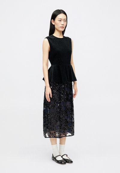 Top peplum negru dintr-un material texturat, asortat cu o fustă lungă până la podea, dintr-un material transparent, împodobită cu paiete negre și modele florale.