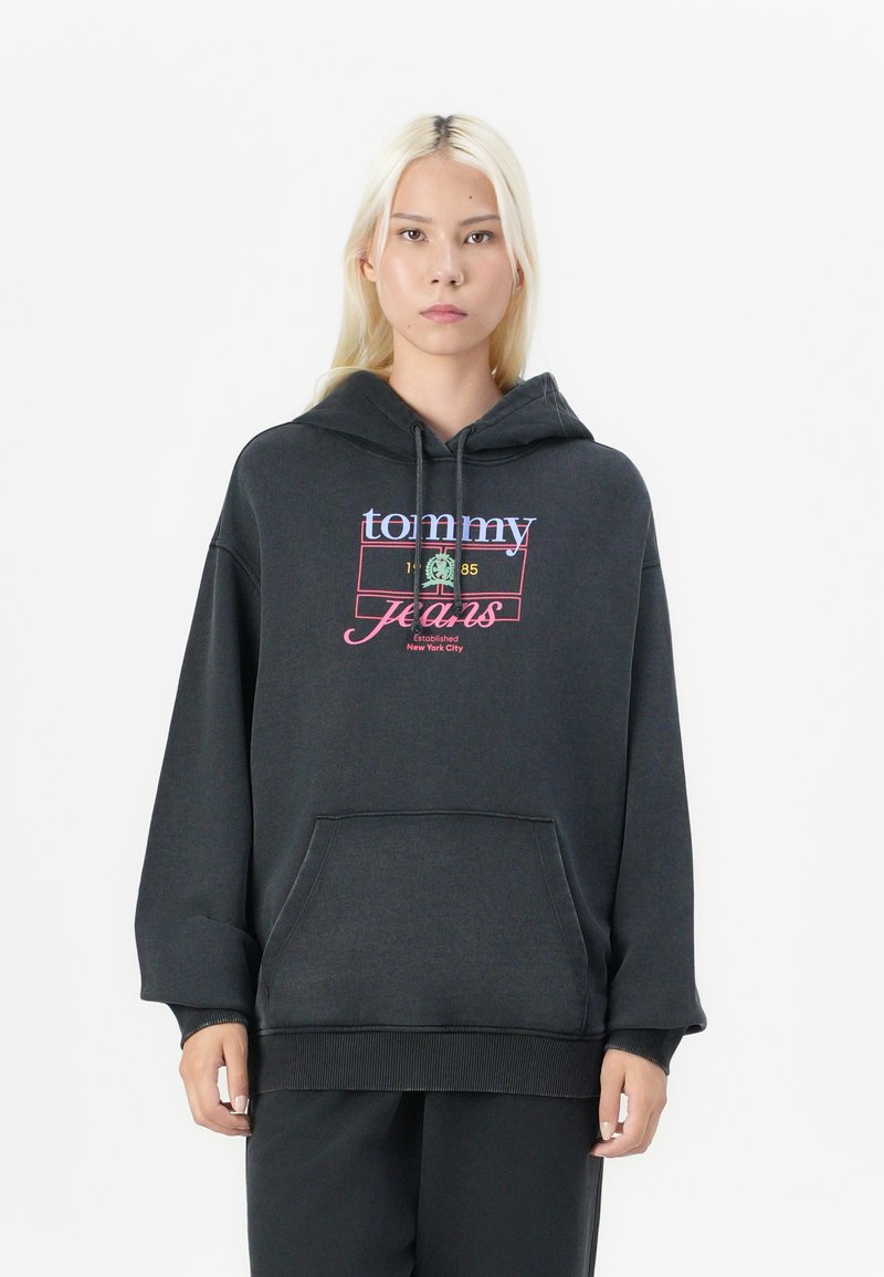Juodas didelės apimties džemperis su priekine ki�šene, su daugiarūšiu „tommy jeans“ logotipu ir kapučino raišteliais. Minkšta, tekstūruota medžiaga.