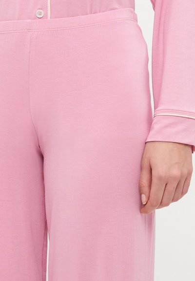 Light pink fabric loungewear set with a relaxed fit. Smooth texture, long sleeves, with button detail at the neckline. Elastic waistband.