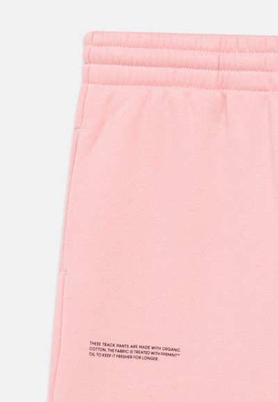 Pantalones deportivos rosas confeccionados con algodón orgánico. Presentan una textura suave, banda elástica en la cintura e instrucciones de cuidado impresas cerca del dobladillo.