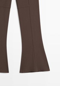 Pantaloni marroni a zampa con cuciture verticali visibili su sfondo bianco.