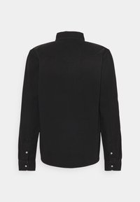Camisa de denim negro con mangas largas, cuello puntiagudo y acentos de botones plateados. Presenta un dobladillo curvado y un diseño de yugo en la parte posterior.