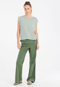 Gestreepte top met korte mouwen in wit en groen, gecombineerd met groene broek met wijde pijpen. De stof lijkt zacht en heeft een ontspannen, casual pasvorm.