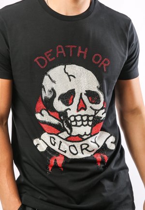 Czarny t-shirt z grafiką czaszki, ozdobioną kryształkami, w czerwonych i białych akcentach, z banerem z napisem "ŚMIERĆ LUB CHWAŁA".