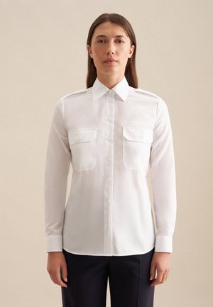 Camicia bianca a maniche lunghe con bottoni, dotata di due tasche sul petto, colletto e maniche con polsini, realizzata in un tessuto liscio con una vestibilità su misura.
