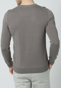 Grauer Strickpullover mit langen Ärmeln und gerippten Bündchen, mit runden Halsausschnitt und figurbetontem Schnitt, von hinten gezeigt.