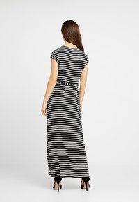 Černobíle pruhované maxi šaty s krátkými rukávy a přiléhavým pasem, vyrobené z měkkého materiálu, s hladkým povrchem a splývavým siluetou.