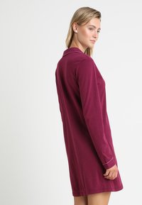 Mauve long-sleeve dress with a collar, featuring a relaxed fit and a solid color. Soft fabric with subtle stitching details at the cuffs.