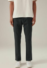 Dunkelgraue lässige Baumwollhosen mit geradem Schnitt und Seitentaschen, kombiniert mit weißen Sneakers und einem hellen T-Shirt.