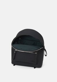 Mochila negra con forma redondeada y exterior texturizado, que cuenta con un cierre con cremallera y un interior espacioso forrado con tela de color verde oscuro.