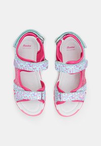 Roosa ja sinine nahast sandaalid, millel on velcro rihmad, südame muster ja sädelusaktsent. Avatud varvaste disain koos pehmendustega tallaga.