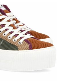 Platform sneakers with a textured corduroy upper in brown, green, and purple, featuring white laces and a ridged white sole.