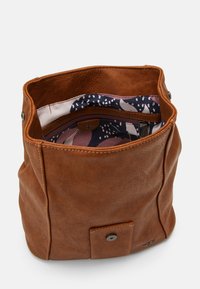 Bruine leren emmer tas met een magnetische drukknoopsluiting en een patroon interieur dat een ritsvak toont.