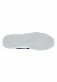 Podplat iz belega teksturiranega gume, ki ima valovit vzorec in logo, zasnovan za oprijem in stabilnost.