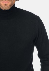 Schwarzer Rollkragenpullover mit schmaler Passform, gestrickter Textur und geripptem Kragen, ausgestattet mit langen Ärmeln und einer glatten Oberfläche.