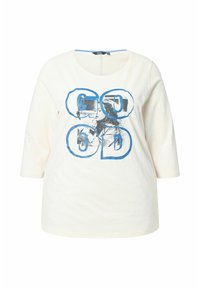 Camisa de manga larga crema con letras azules contorneadas que dicen "GOOD" sobre una foto en blanco y negro de dos personas besándose en el frente.