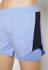 Ljusblå sportshorts med en svart mesh-sidopanel, med en elastisk midja och en subtil logotypdetalj på tyget.