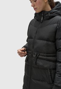 Black puffer jacket with a front zipper, hood, and side pockets. Features a quilted texture and adjustable drawstrings at the collar.