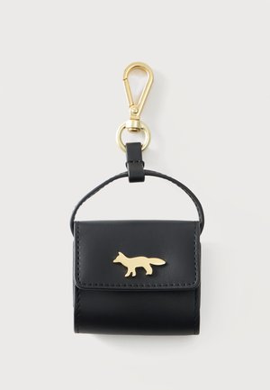 Pochette à clés en cuir noir avec emblème de renard doré et clip métallique doré pour l'attacher aux sacs ou aux clés sur un fond uni.