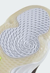 Sål med en struktureret hvid gummioverflade med cirkulære og ovale udskæringer, omkranset af gennemsigtig tan gummi for greb og fleksibilitet.