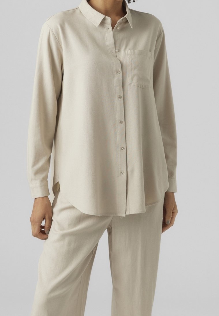 Beige Langarm-Hemd mit Knöpfen, Kragen und einer Brusttasche. Weicher Stoff, lockere Passform, abgerundeter Saum und einfache Knopfverschluss.