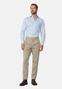Lichtblauw overhemd met knopen en een subtiel streepjespatroon, gecombineerd met beige op maat gemaakte broeken en bruin leren laarzen. Rechte pasvorm.