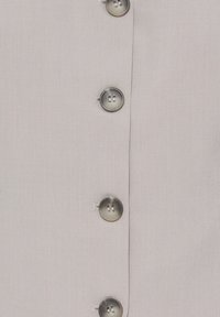 Tissu beige clair avec une rangée verticale de cinq boutons ronds gris translucides cousus avec quatre trous.
