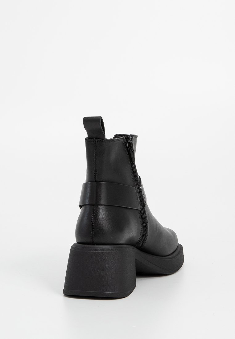 Zwarte leren enkelboot met een blokhak, voorzien van een zijrits en een brede band rond de hak. Glad oppervlak en minimalistisch ontwerp.