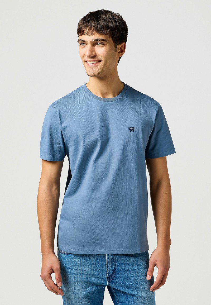 Lichtblauw T-shirt met korte mouwen van katoen, met een ronde hals en een klein logo op de borst. Gemaakt met blauwe jeans.