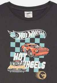 Graues Baumwoll-T-Shirt mit "Hot Wheels" Grafik, zwei bunten Rennwagen und kariertem Muster in Minzgrün und weißen Akzenten.