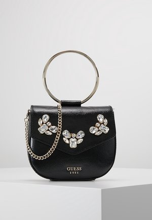 Sac à main noir Guess avec chaîne dorée et poignée anneau, décoré de trois grappes d'ornements de pierres précieuses transparentes sur le rabat avant.
