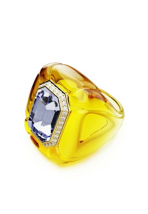 Gelber Harzring mit einem oktagonalen blauen Edelstein, umrandet von einem Ring kleiner klarer Steine, mit einer glatten, glänzenden Oberfläche.