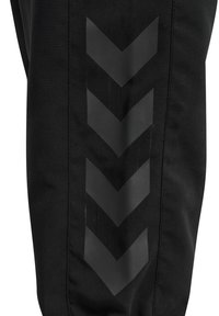 Schwarze Sporthose mit einem mattschwarzen Zickzackmuster an der Seite, aus einem glatten, leichten Stoff mit strukturiertem Sitz.