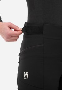 Pantalons techniques noirs avec une poche zippée à l'avant, une taille ajustable avec Velcro et un logo visible sur le bas de la jambe. Texture lisse.