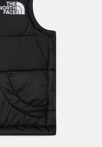 Gilet imbottito nero con design trapuntato, dotato di una tasca curva, collo alto e logo bianco ricamato sulla zona del petto.