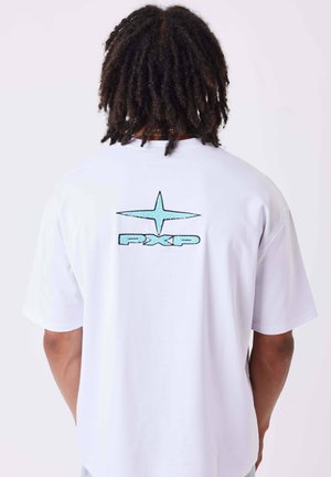 Homme avec des dreadlocks portant un t-shirt blanc avec une étoile bleu clair et le logo "PXP" sur la partie supérieure du dos sur fond uni.
