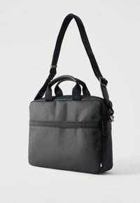 Μαύρη υφασμάτινη τσάντα φορητού υπολογιστή με διπλές λαβές και ρυθμιζόμενο ιμάντα ώμου, εμφανίζεται πάνω σε απλό ανοιχτό φόντο.