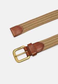 Cinturón trenzado color marrón de Levi's con punta de cuero marrón y hebilla de metal dorado. La textura es acanalada; la hebilla presenta un diseño cuadrado.