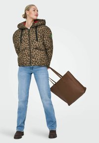 Leopard-print puffer jacket with a red lining, black drawstring, light blue jeans, and a brown tote bag. Smooth fabric and relaxed fit.