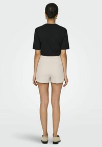 T-shirt noir à manches courtes associé à un short beige. Le short présente une taille haute et une texture lisse, conçu pour le confort et la facilité.