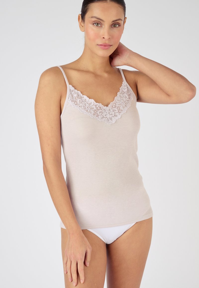 Top sin mangas de color beige claro con tirantes ajustables, que presenta un escote de encaje floral. Tela suave y ajustada, combinada con ropa interior blanca.