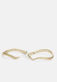 Pendientes de metal color oro con un diseño curvado y minimalista. Presentan una punta afilada en un pendiente y una forma suave y redondeada en el otro.
