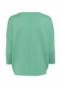 Mėtų žalios spalvos megztinis su laisvu siluetu, trijų ketvirčių ilgiais rankovėmis ir tiesiu apvadimu. Nugaroje yra centrinė siūlė.