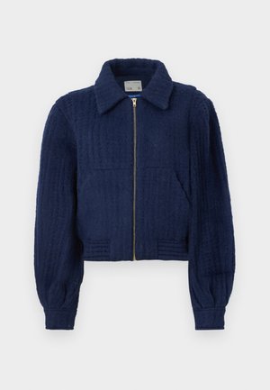 Marineblå cropped jakke laget av teksturert stoff, med glidelås foran, krage og to frontlommer. Elastiske mansjetter med ribbede detaljer.