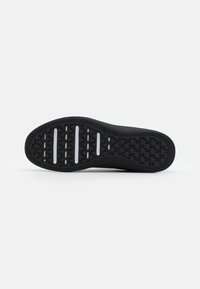 Suela de zapatilla negra con textura, que presenta ranuras horizontales y patrones de logo, bordes lisos y un material de goma resistente.