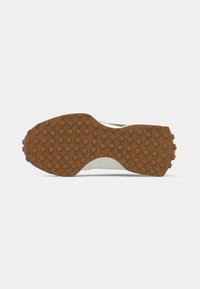 White sneaker with a textured tan rubber outsole featuring circular treads, revealing simple, rounded design and minimalistic lines.